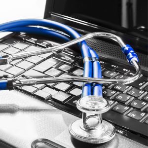 A doctor's stethoscope lying on top of a computer keyboard